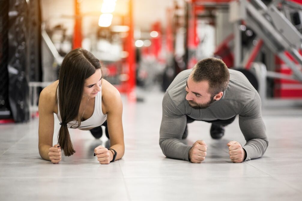 Bir erkek ve kadın, tüm kas grupları için tasarlanmış plank egzersizini gerçekleştirir. 
